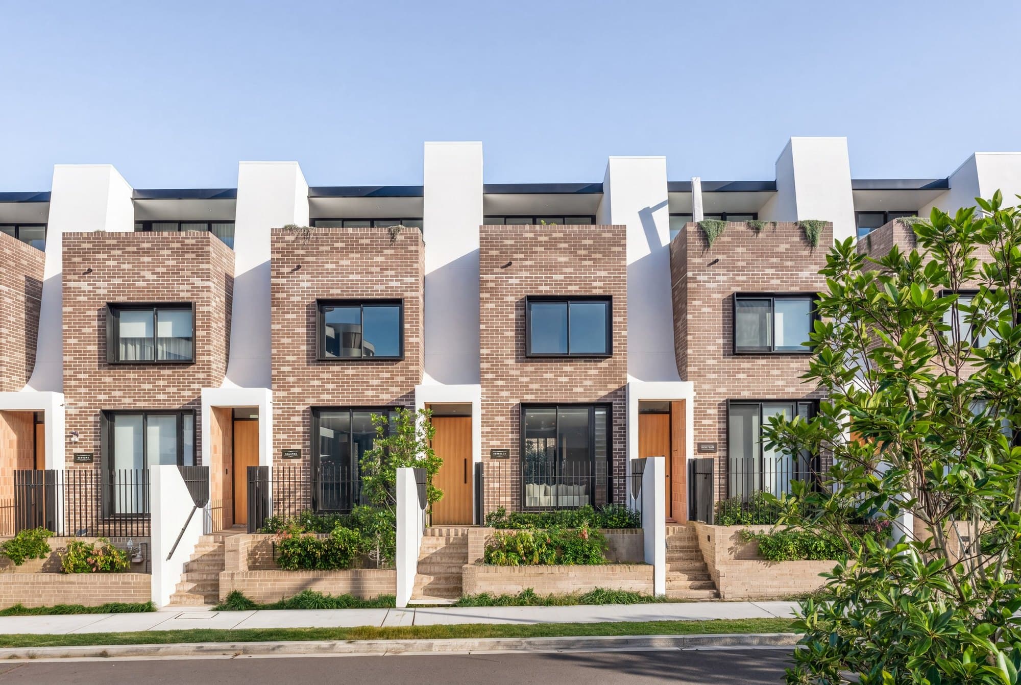 Row of brick townhomes with timber front doors at Jane Street Terraces